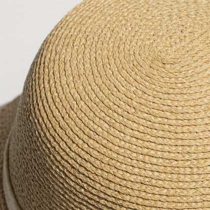 Close-up view of handwoven straw texture showing tight spiral weave pattern under natural light.