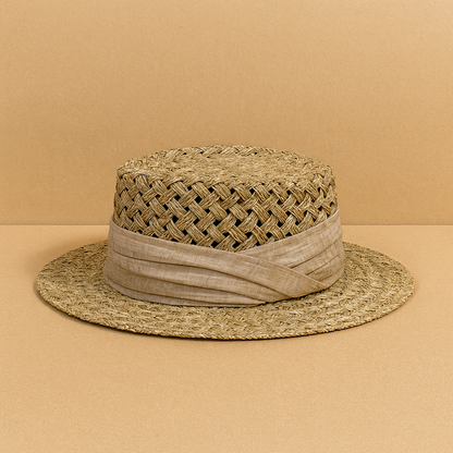 Handwoven vintage-style straw sun hat with a beige fabric band, displayed on a warm neutral background.