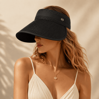 Blonde model wearing a black wide brim straw visor in soft sunlight for a modern summer look.