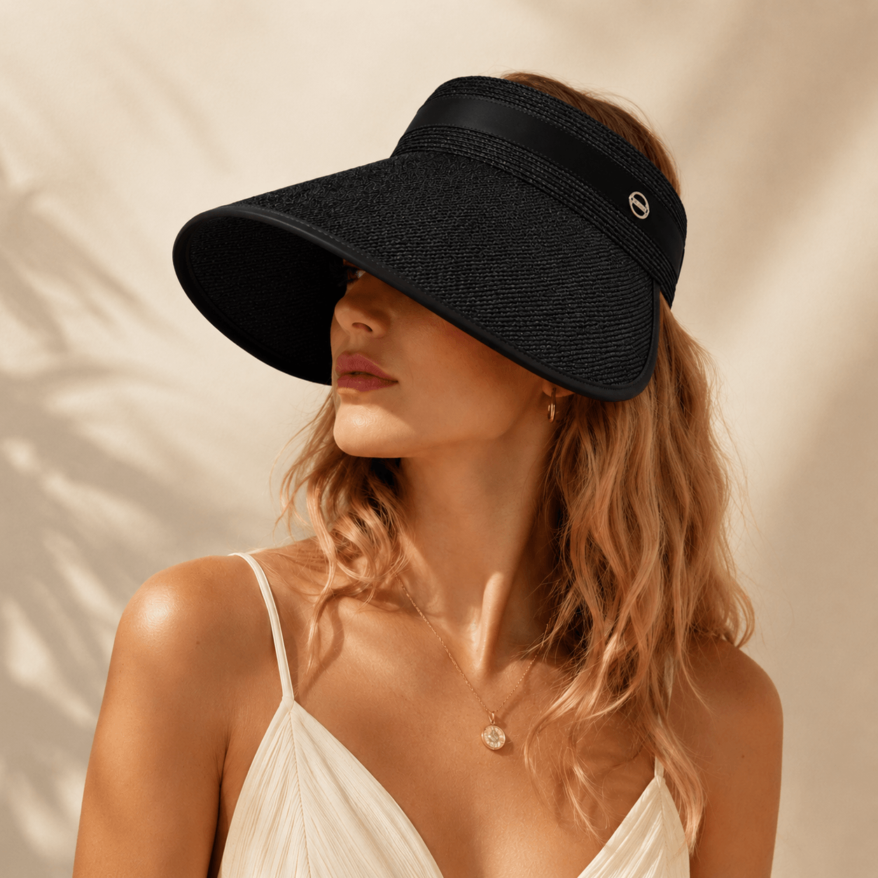 Woman wearing a black raffia wide brim sun visor styled with a white summer dress.