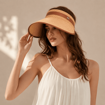 Woman wearing a khaki raffia wide brim sun visor styled with a light summer dress for a resort-ready look.