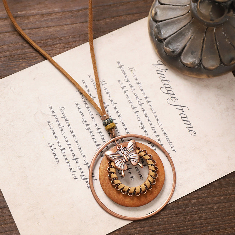 Vintage butterfly wooden necklace with circular layered rings and suede cord displayed on wood table.