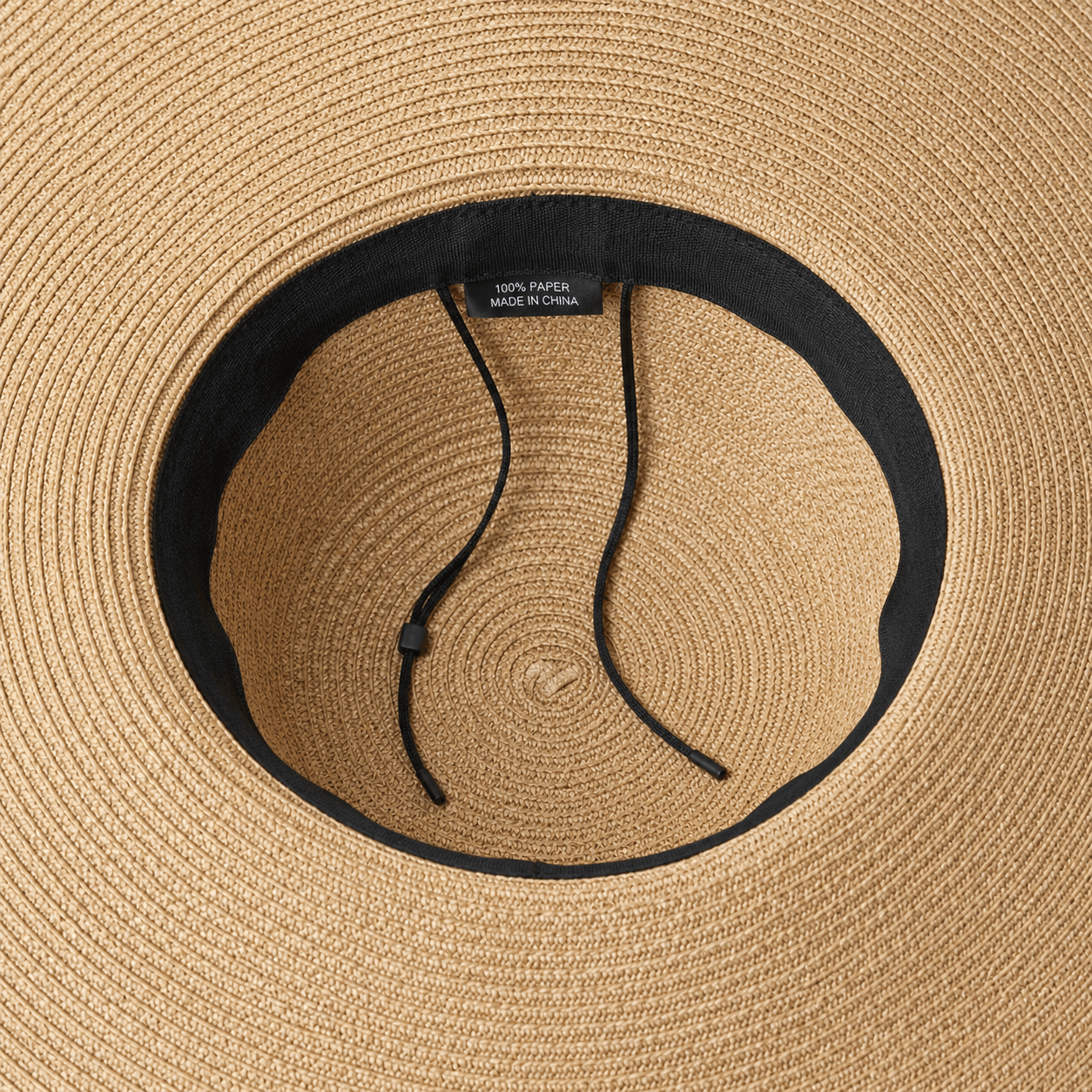Inside view of an oversized straw sun hat showing the adjustable inner band and drawstring detail