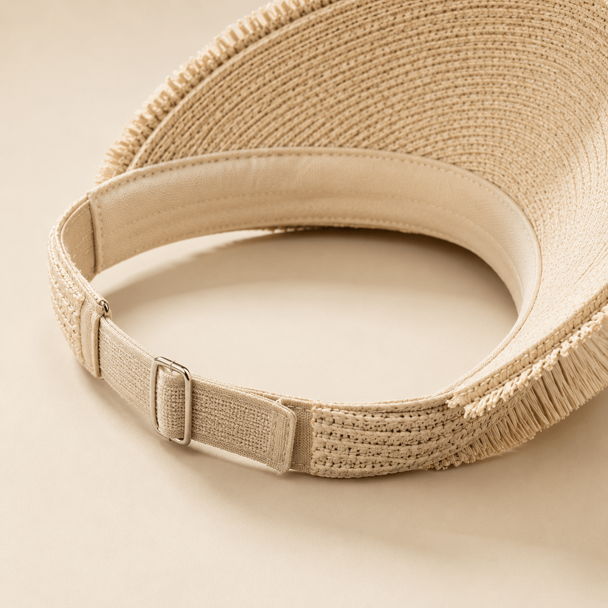 Inside back view of a straw visor hat showing the adjustable strap and open-top design