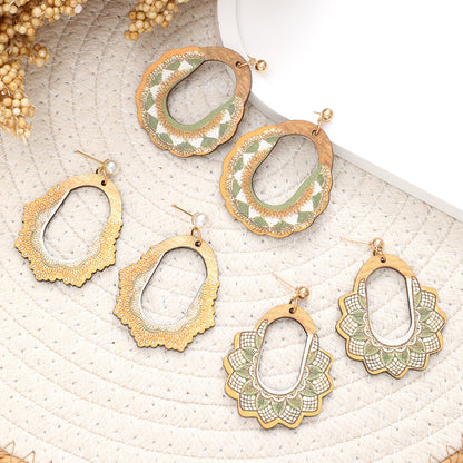 Set of assorted wooden earrings in green and white boho designs laid out on round woven mat.
