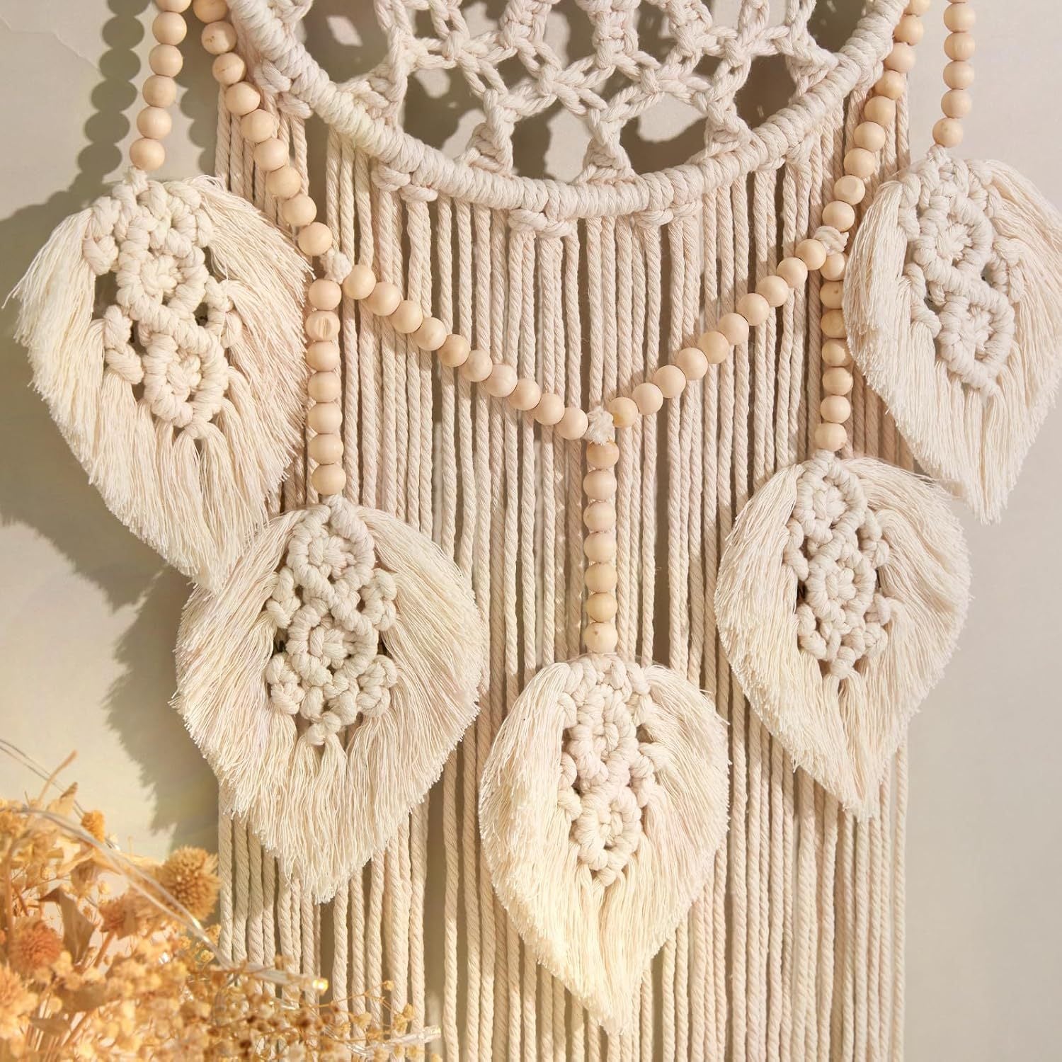 Detailed view of hand-knotted leaf fringe and wooden beads on the macrame wall hanging.