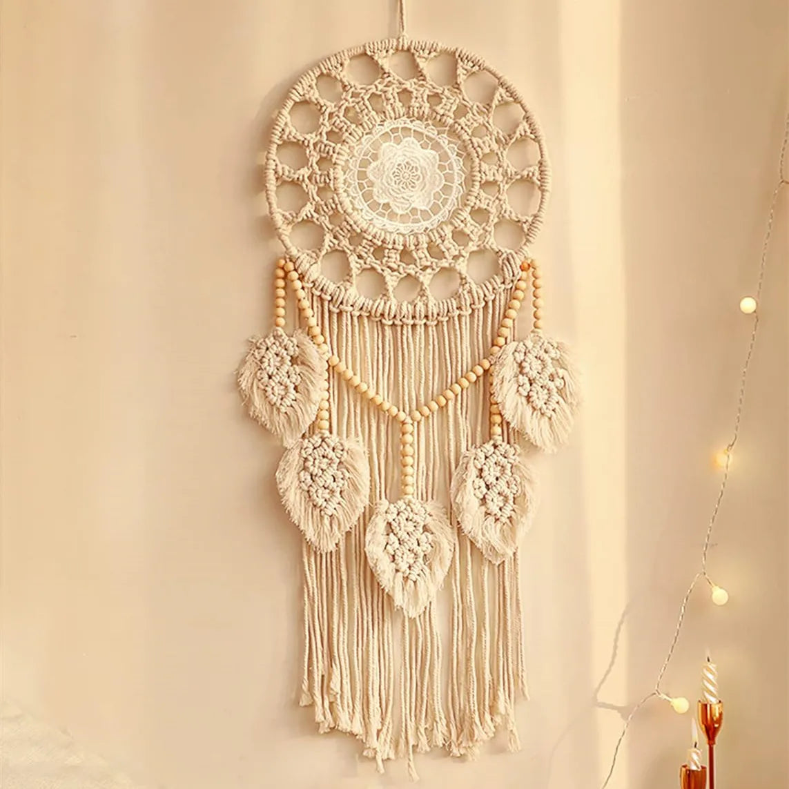 Cream-colored boho macrame wall tapestry with crochet and fringe details under warm ambient lighting.