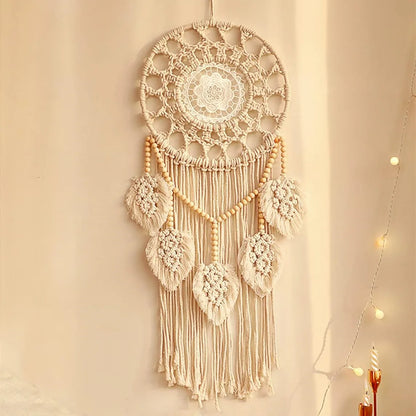 Cream-colored boho macrame wall tapestry with crochet and fringe details under warm ambient lighting.