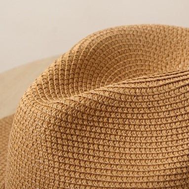 Top view close-up of brown woven straw hat crown showing fine texture and natural weave pattern.