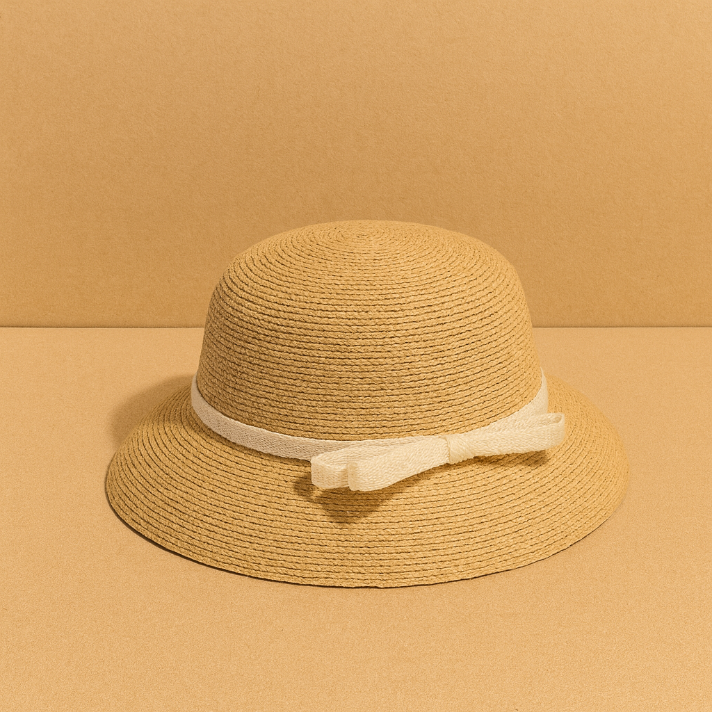 Classic woven straw hat with cream bow detail, displayed on warm beige background for a minimalist summer look.