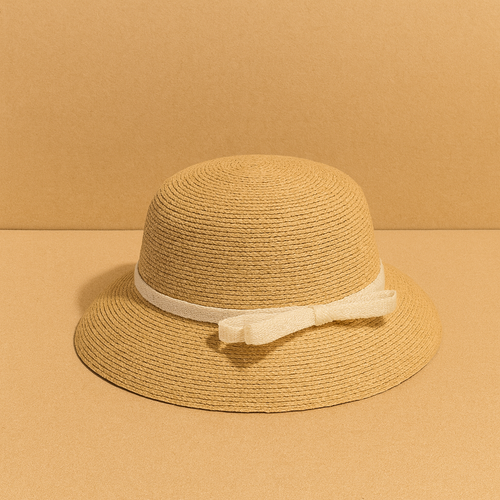Classic woven straw hat with cream bow detail, displayed on warm beige background for a minimalist summer look.