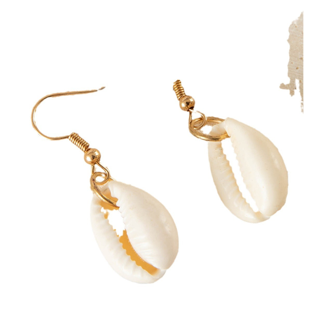 Pair of cowrie shell earrings with golden hooks on white background.
