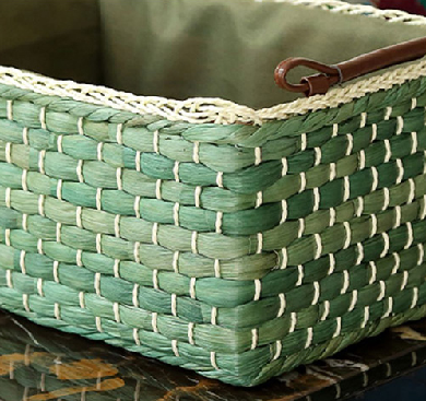 Detailed corner view showing the texture and tight weave of the green straw basket with cream trim.