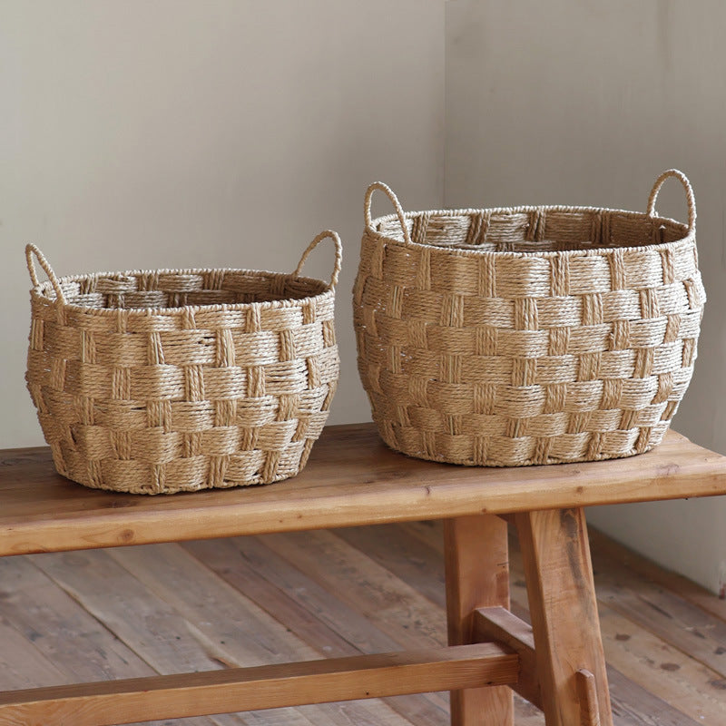Two woven straw storage baskets in different sizes placed on a wooden bench, natural lighting and rustic interior.