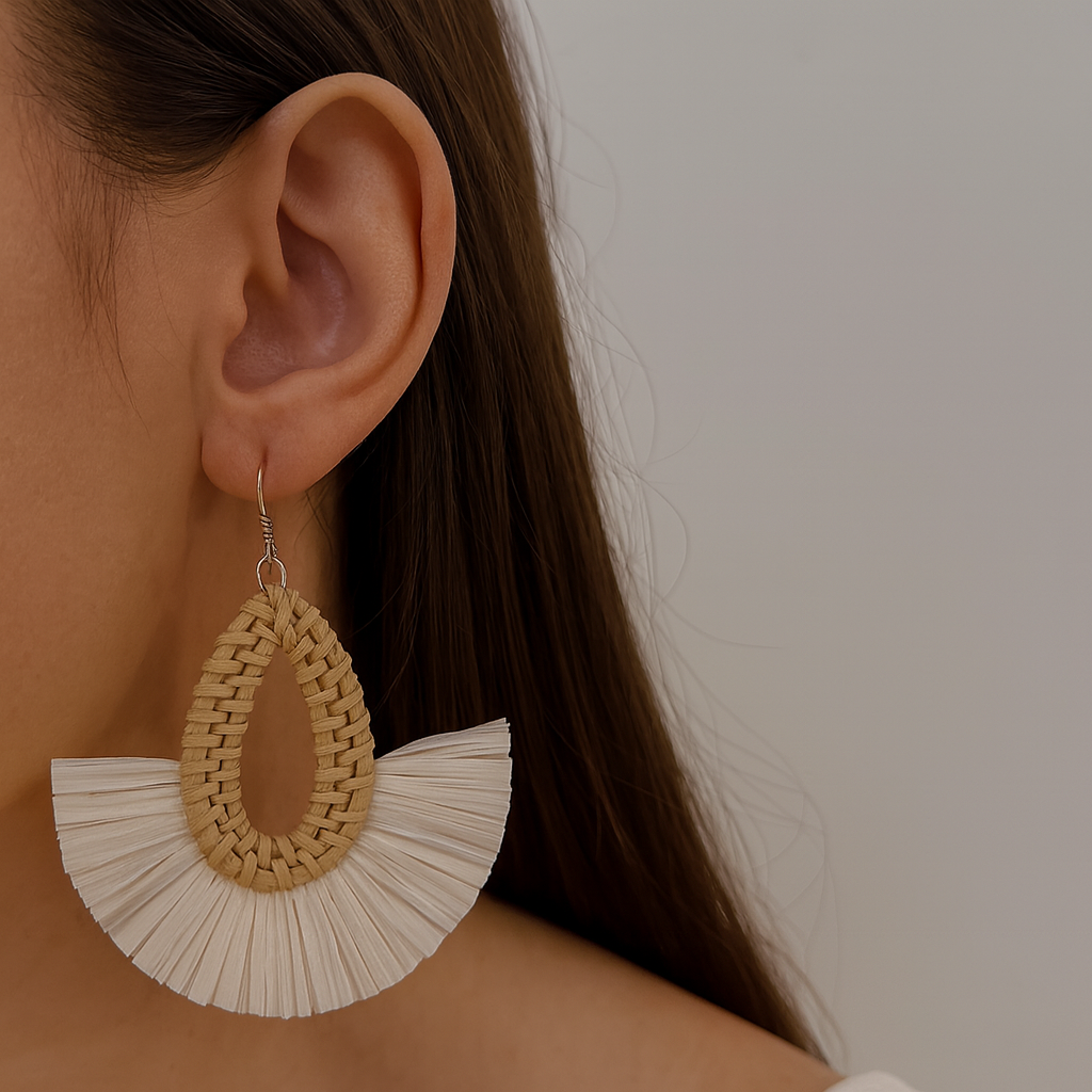 Handmade rattan teardrop earring with raffia fan detail shown on ear in soft natural light.