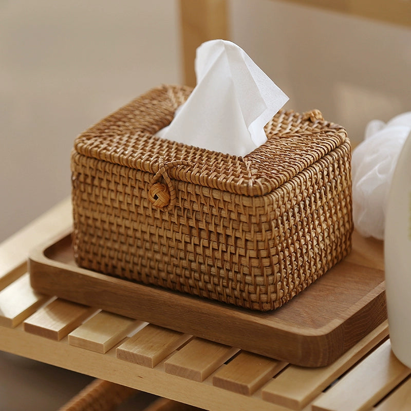 Handmade rattan tissue box with tissue inserted, placed on light wooden shelf in a cozy natural setting.
