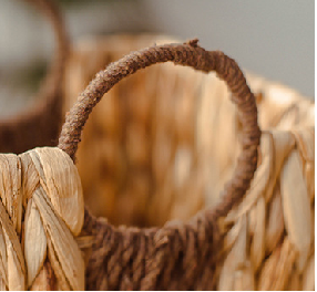 Close-up of the circular rope handle wrapped in brown fiber on a gourd grass storage basket.