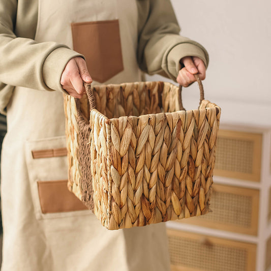 Person holding a hand-woven gourd grass storage basket with braided handles, natural tone and rustic texture.
