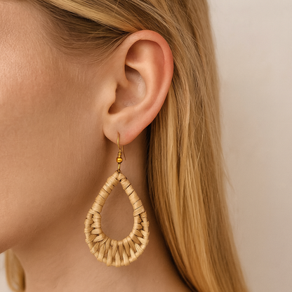Handwoven rattan teardrop dangle earring worn by woman with blonde hair in natural light.