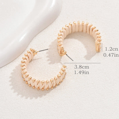 Size reference of handwoven straw hoop earrings with gold details on light surface.