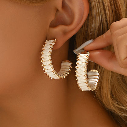 Woman wearing handwoven straw hoop earrings with gold detailing in bohemian style.