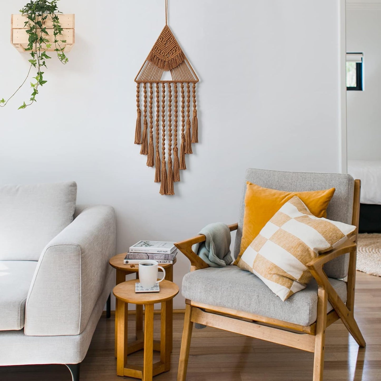 Boho-style macrame wall hanging displayed in cozy living room with wooden furniture and warm tones.