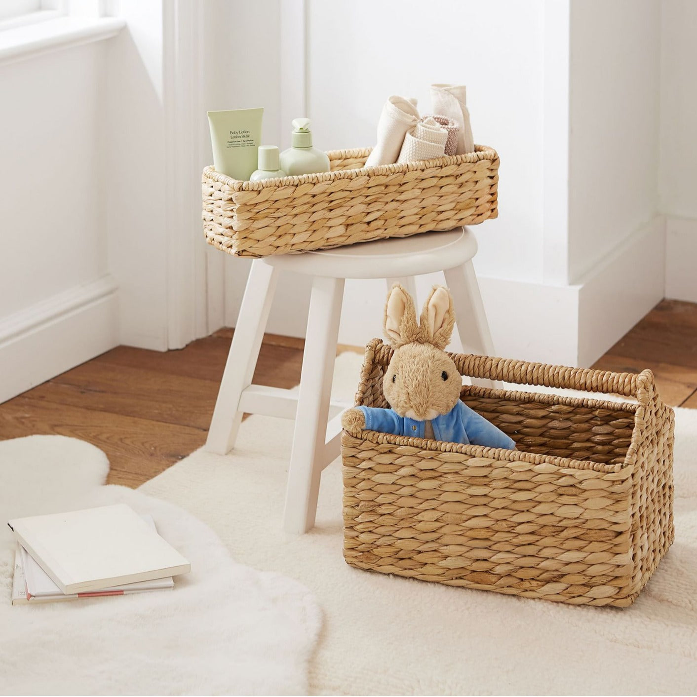 Water hyacinth storage baskets placed in a bright room, one holding a toy rabbit and one with baby care items on stool.