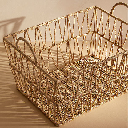 Empty rectangular rattan laundry basket showing open lattice weave and shadow lines from sunlight.