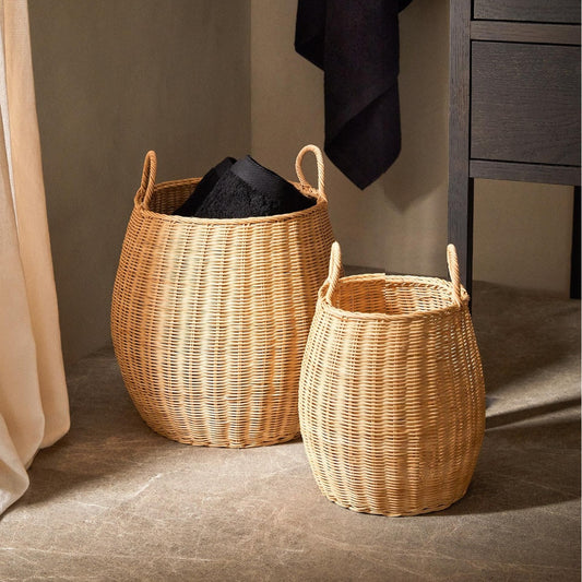 Two handwoven rattan laundry baskets with towels in a bathroom scene, large and medium sizes with loop handles.