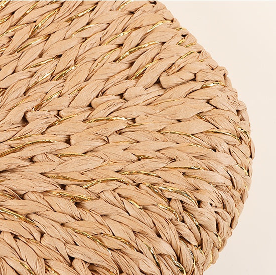 Close-up of the rounded bottom of the handwoven straw tote bag, showing even weaving and gold accent fibers.