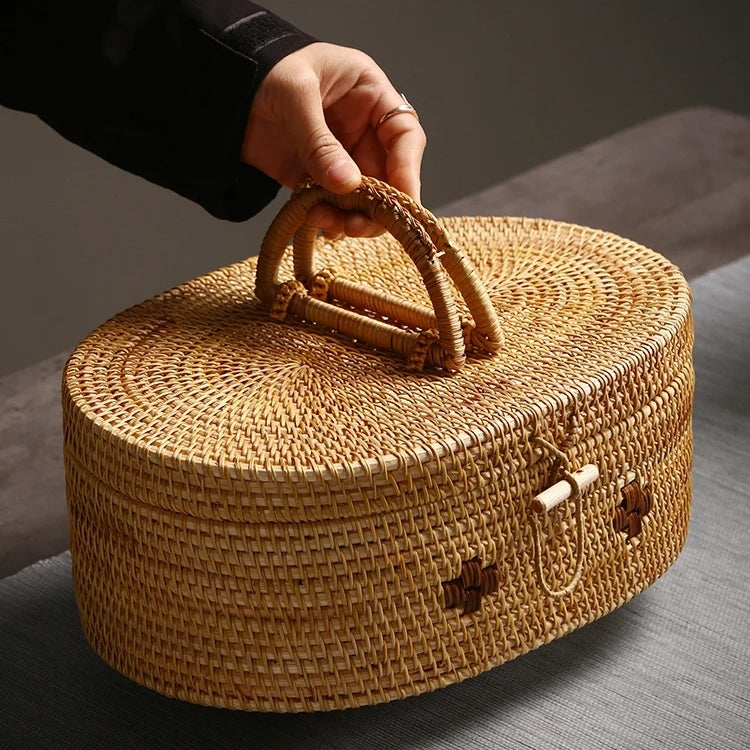 Person holding a large oval rattan storage box by its woven handle, showcasing portability and craftsmanship.