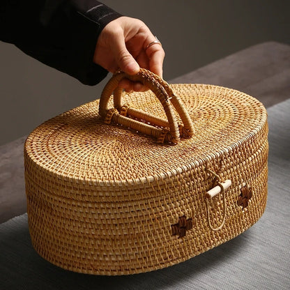 Person holding a large oval rattan storage box by its woven handle, showcasing portability and craftsmanship.
