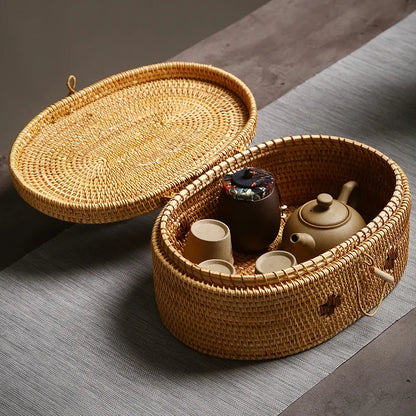 Open rattan storage box containing teapot and cups, displayed on gray table runner for home tea storage.