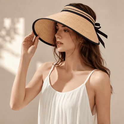 Woman wearing a light coffee wide brim paper straw visor hat with black trim and ribbon tie