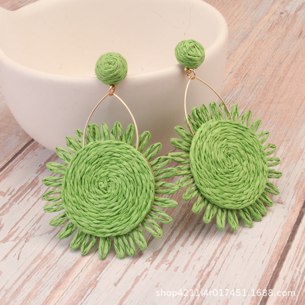 Light green natural Lafite grass sunflower earrings with bohemian woven design and gold wire loop.