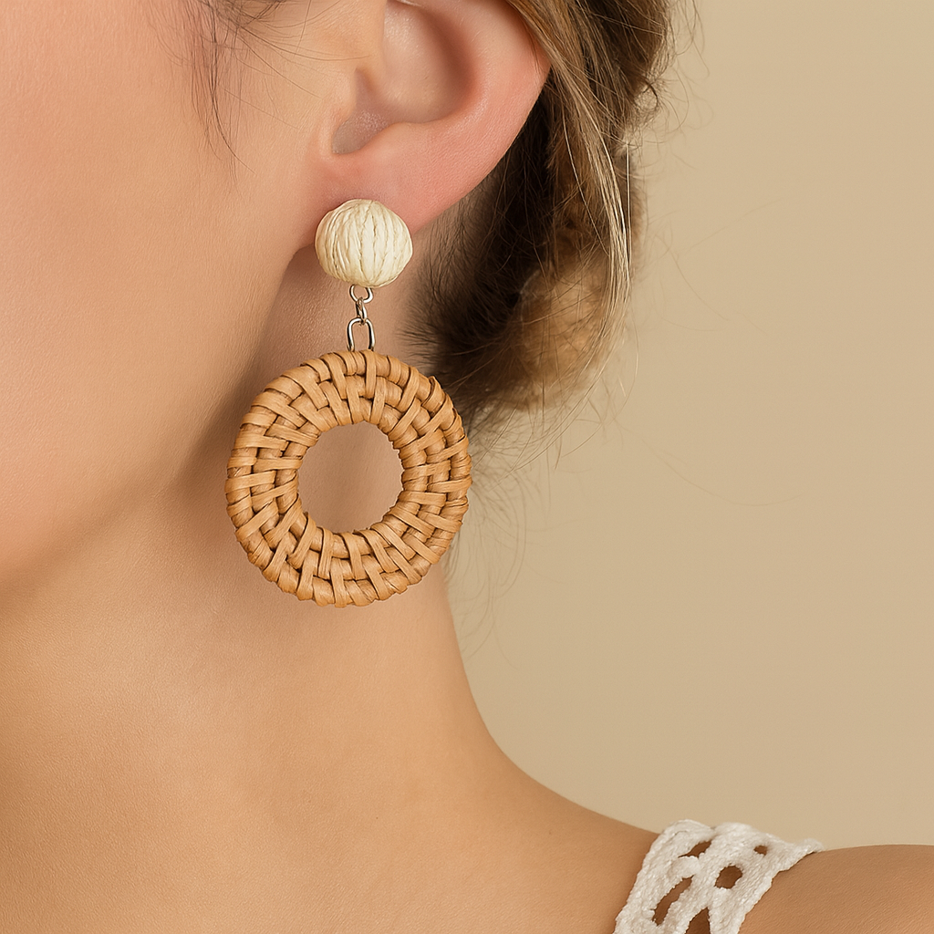 Round rattan weave earring with natural fiber bead worn by woman with updo hairstyle.