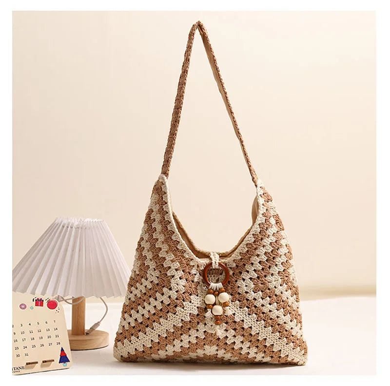 Brown and beige crochet cotton shoulder bag displayed on a soft neutral background beside a desk lamp and calendar