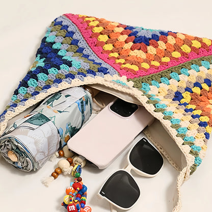 Open crochet shoulder bag with visible items inside, including phone, sunglasses, and small accessories.