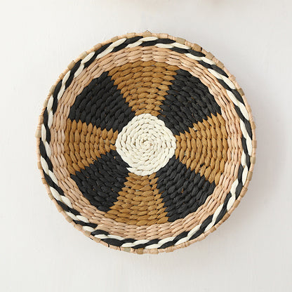 Handcrafted seagrass wall plate with black and tan radial geometric pattern and braided edge.