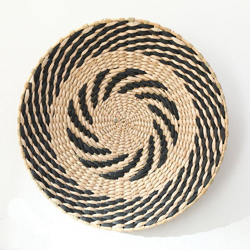 Natural raffia wall plate with alternating black and beige spiral pattern, handwoven in boho style.