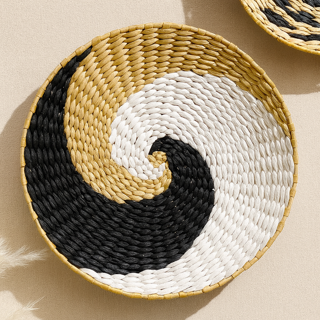 Close-up of yin-yang patterned handwoven wall plate made from natural straw in beige, white, and black tones.