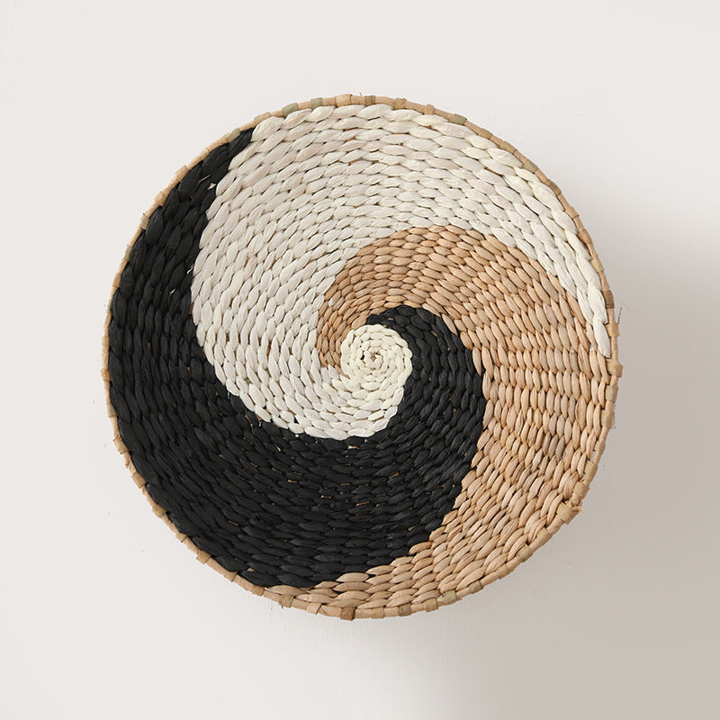 Yin-yang inspired wall basket made from handwoven raffia in natural, white, and black tones.