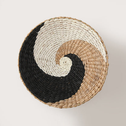 Yin-yang inspired wall basket made from handwoven raffia in natural, white, and black tones.