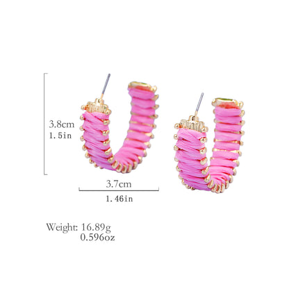 Pink handwoven straw hoop earrings with gold accents and size measurement.
