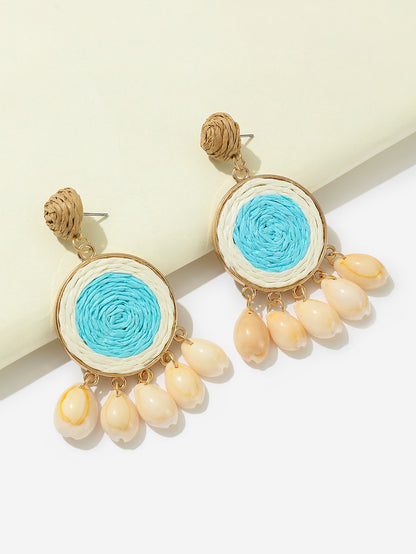 Sky-blue raffia-woven shell earrings with gold details photographed on white background.