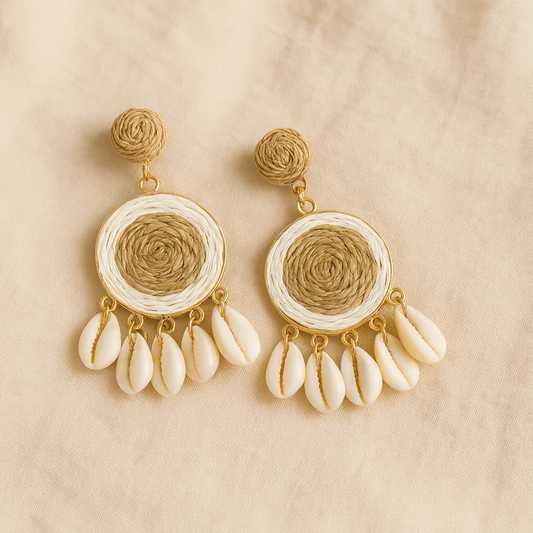 Pair of raffia-woven round shell earrings with natural beige and white tones on linen background.