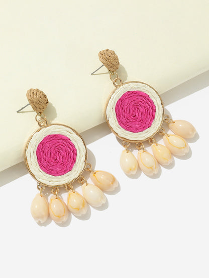 Pink raffia-woven shell earrings with natural shell drops displayed on white background.