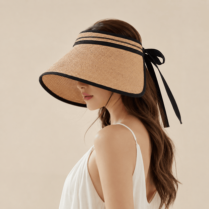 Side view of a woman wearing a paper straw visor hat with black contrast trim and back ribbon tie