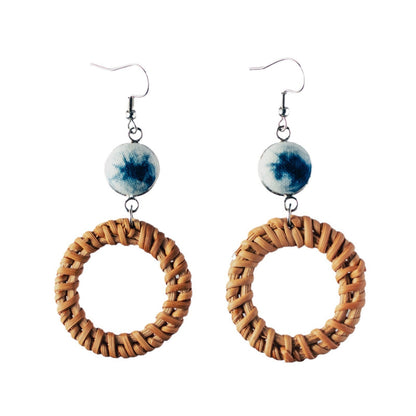 Handwoven circular rattan earrings with indigo-blue ceramic beads and hook closure.
