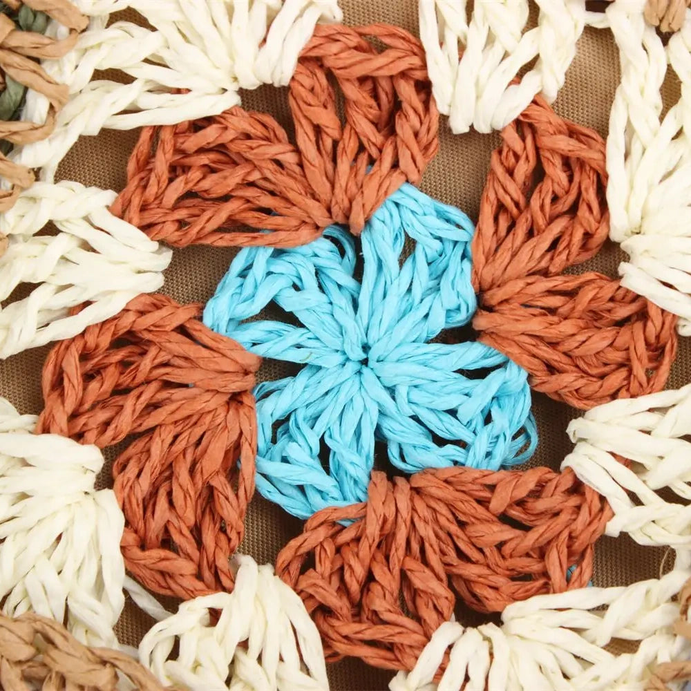 “Close-up of single crochet flower motif in blue, brown, and cream tones on embroidered straw bag, by Solmerea.”